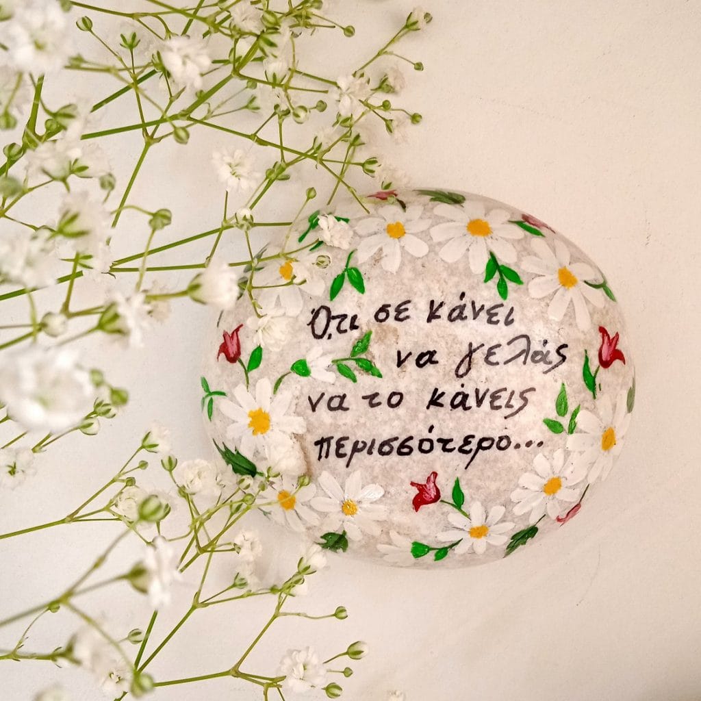 Ζωγραφισμένο βότσαλο με θετικό μήνυμα και λουλούδια